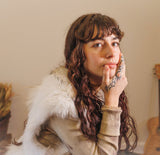 "Woman with hand tattoos posing indoors – Kiwi Glow Kavai Tattoo Oil keeps tattoo ink bright and skin luminous all day"