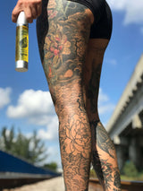 Full legs Tattoo holding a bottle of kavai tattoo oil