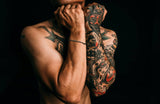 “Man with vibrant, detailed full-sleeve tattoos showing healed tattoo ink and healthy skin.”