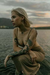 Tattooed woman sitting outdoors with healed arm tattoos, natural skin texture, representing tattoo aftercare and long term ink care