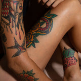 Close-up of healed tattoos on arms and thigh, showing vibrant traditional tattoo designs on healthy, well-moisturized skin