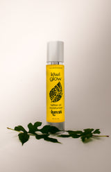 Kiwi Glow's Kavai Tattoo Oil sits in a white space with a green leaf in the foreground. The bottle is yellow and has the Kiwi Glow Leaf Logo on the center area of the bottle. It reads: "Kiwi Glow... Tattoo Oil Moisturizer... Kavai...net 4 fl oz."