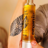 Kiwi Glow's Kavai Tattoo Oil resting against someone's forearm as if on display. Light colors are prominent thorughout the image.